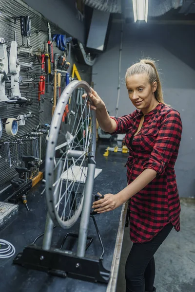 Female technician in her bicycle repair shop. Female Bicycle Mechanic. Woman repairing bicycle in garage. Technician woman fixing bicycle in repair shop