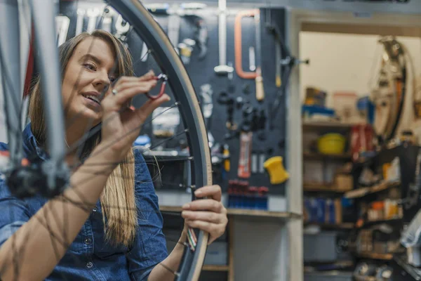 专注于收紧自行车轮胎 在修理厂修理自行车时 警惕的技师 女孩修理自行车轮子 骑自行车的女自行车技工 — 图库照片