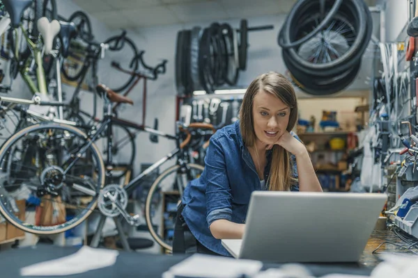 Creativity is a process. Woman mechanic working on a laptop. Female Bicycle Mechanic. Female mechanic in bicycle store. Young female mechanic with laptop