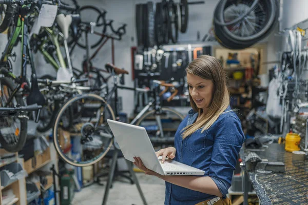 年轻的女技工与笔记本电脑 在工厂的女商人 在笔记本电脑上工作的女技工 女自行车技工 — 图库照片