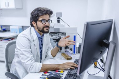 Bilgisayarda çalışan Office erkek doktor. Gülümseyen erkek Doktor tıbbi ofiste bilgisayar kullanarak. Bilgisayar ile neşeli doktor