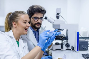 İki biotechnologists bir laboratuvar araştırma üzerinde çalışırken iletişim. İş arkadaşları üzerinde bilimsel araştırma laboratuvarında çalışıyor. Bilim, kimya, teknoloji, biyoloji ve insanlar kavramı