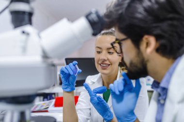 İki bilim adamları laboratuarda çalışıyoruz. Genç bilim adamları klinik laboratuvar ve Not almak test veya araştırma yapmak mikroskop ile. Bilim, kimya, teknoloji, biyoloji ve insanlar kavramı