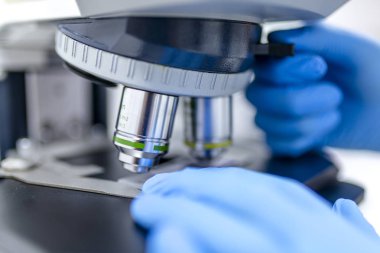 Mikroskop, örnekleri inceleyerek bilim adamı elle. Arka plan örnekleri üzerinde bir araştırma laboratuvarı modern mikroskobu sınavı-cam şişeler için.