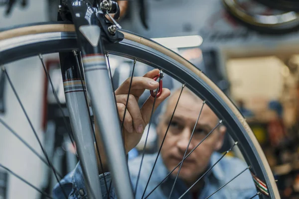 Service for bike with adept repairing bike. Bicycle mechanic in a workshop in the repair process. Stylish bicycle mechanic doing his professional work in workshop.