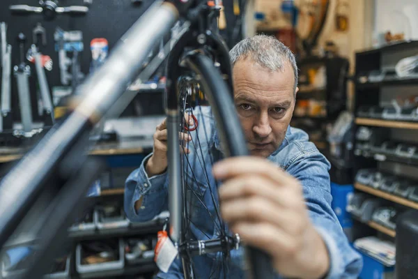 Service for bike with adept repairing bike. Bicycle mechanic in a workshop in the repair process. Stylish bicycle mechanic doing his professional work in workshop.