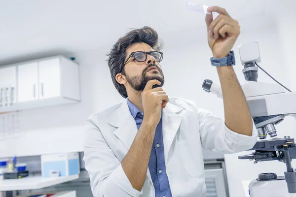 Lab technician looking at samples very focused holding the samples up close to him. Scientist looking at the scientific sample in the CDC laboratory