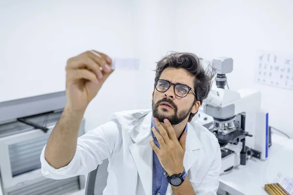 Scientist Looking at a Microscope Slide. Concenrated scientist working with microscope in laboratory. Doctor doing medical research medical samples, at the lab