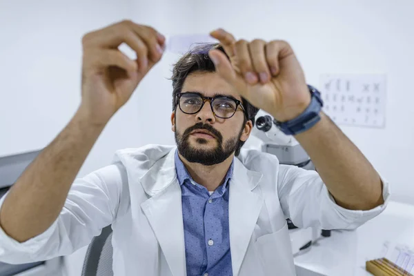 Scientist analyzing microscope slide at laboratory. Man Working in Laboratory With Microscope. Scientist examining slide. Concenrated scientist working with microscope in laboratory