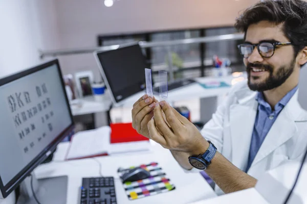 Researcher in the lab looking on microscope slide. Works with the microscope slide.  Attractive young male scientist looking at the microscope slides in laboratory.