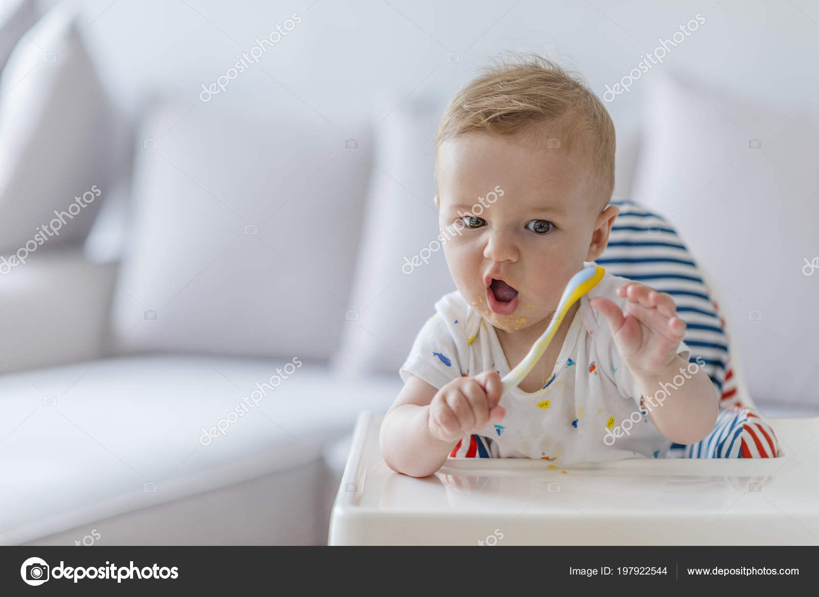 Baby Sitting Highchair All Messy Eating Orange Food Spoon Baby Sitting In Highchair All Messy Eating Orange Food With Spoon Mouth Small Child Sits On A Chair And