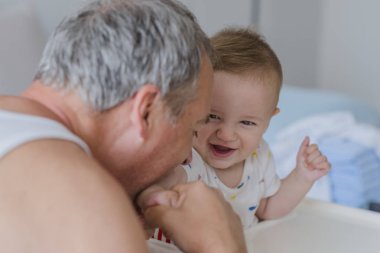 Bir adam oğluyla vakit geçiriyor. Seven baban ile evde bir bebek. Mutlu baba bebek ile oynuyor. Baba ile bebek. Baba ve oğul