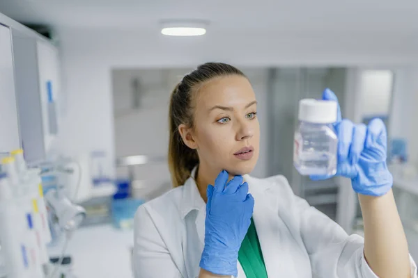 Young female lab technician conducting science researching. Female researcher carrying out research experiments in a chemistry lab. One female scientist researcher making research in chemistry laboratory