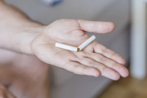 Quit bad habit, health care concept. No smoking. Concept photo of a man quitting smoking by breaking a cigarette. Male hand crushing cigarette. Man trying to quit smoking. Conceptual image