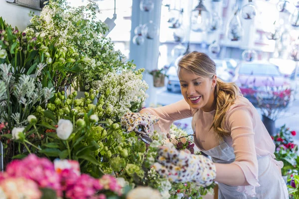 Professional florist working in flower shop. Florist shop in daylight. Woman holding beautiful bouquet of flowers. Florist with her work