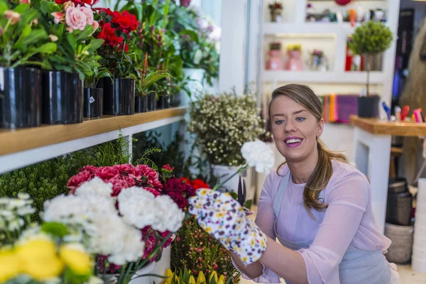 Smiling woman florist small business flower shop owner. Small business concept with florist woman ownership on modern flower shop. Flowers delivery, creating order.