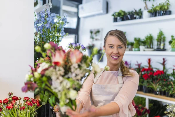 花店的柜台上的花店的肖像 送花花束的年轻妇女 在花店的柜台上 一个快乐的花店提供和出售鲜花的肖像 花店给 Cli 美丽的花束 — 图库照片