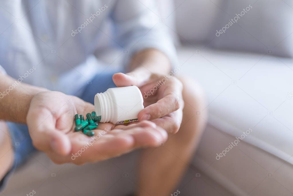 Male hand holding a medicine. Man hands with pills on spilling pills out of bottle. Medicine and health care concept. Man hand holding frug medicine bottle on Herbal supplement pill,eating healthy