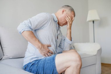 Adam mide karın ağrısı veya gastroenterolog. Sağlık ve tıp konseptiyle. Mutsuz adam evde mide ağrısı acı