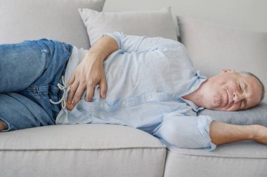 Olgun adam mide ağrısı, mide acı ifadesi ile basarak. Mutsuz adam evde mide ağrısı acı. Adam karın ağrısı acı. Sağlık kavramı. 