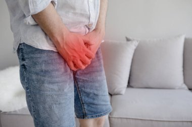 Genç adam tutarak onun genital neden ağrı, prostat kanseri, erken boşalma, doğurganlık, mesane sorunu kapatın. Pantolon orta kasık üzerinde tutan adam el 