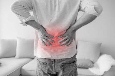 Sırt ağrı, tek renkli fotoğraf kırmızı Sertleştirme için bir sembol olarak tutan bir adamın kapatın. Adam gri arka plan üzerinde sırt ağrısı muzdarip. Sağlık kavramı