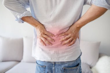 Dikiz sırt ağrı, tek renkli fotoğraf kırmızı Sertleştirme için bir sembol olarak tutan genç bir adam. Sırt ağrısı dokunmadan eller yukarı kapatın