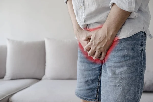 Boy is suffering and holding his genitals on white background with copy space. Man Covering His Crotch. Male suffering with pain in the urogenital system. Disease for men. — Stock Image Boy Suffering Holding His Genitals White Background Copy Space Man Stock Photo