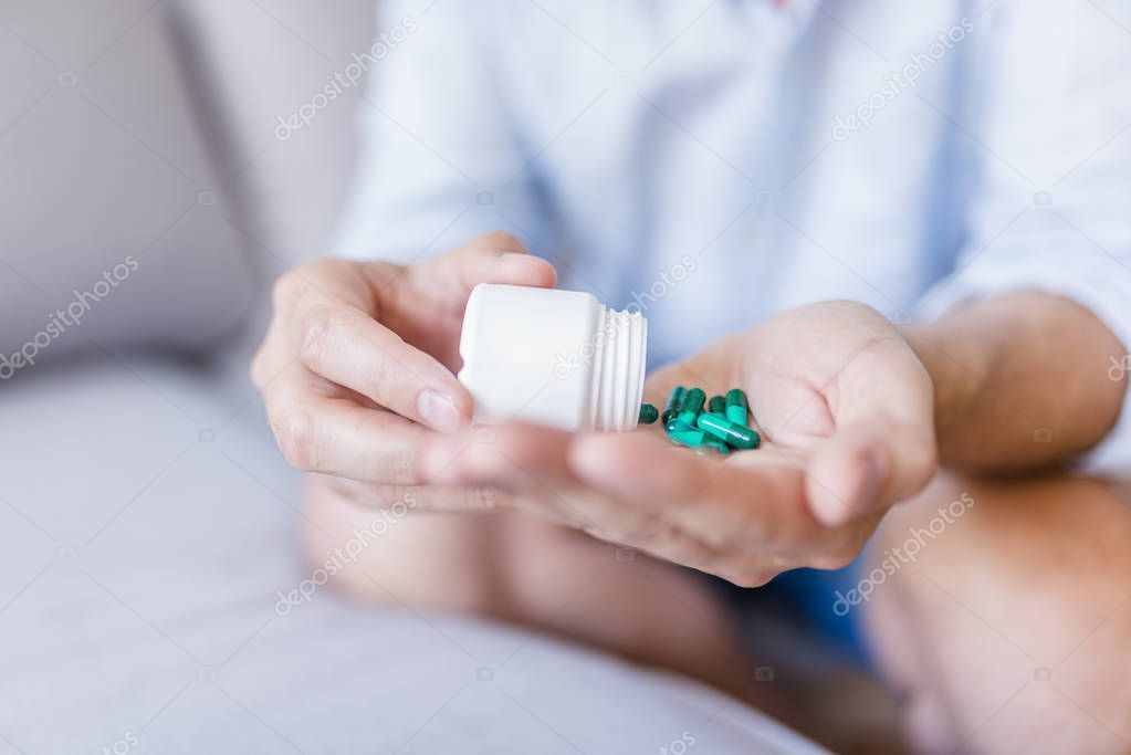 Closeup on man's hands with pills. Healthcare and medical concept. Man taking pills. Bottle pouring pills on a male's hand. Person taking different types of drugs. Medication in Hand