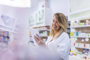 Kadın eczacı İlaç eczanede dijital tablet kullanırken arama 