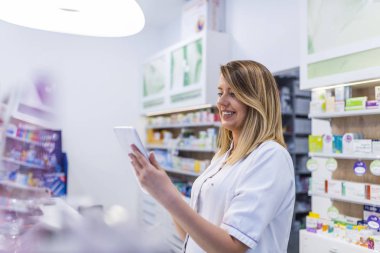 Kadın eczacı İlaç eczanede dijital tablet kullanırken arama 