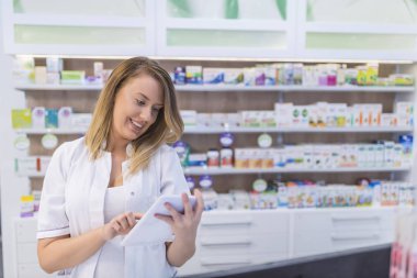 Kadın eczacı İlaç eczanede dijital tablet kullanırken arama 