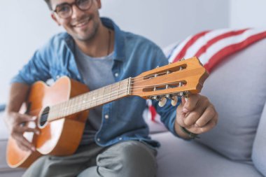 Kanepede oturan ve gitar çalmak genç adam portresi