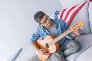 Kanepede oturan ve gitar çalmak genç adam portresi