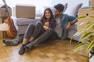 Yeni ev karton kutular ile katta oturan genç Çift 