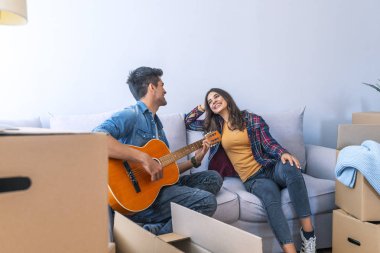 Genç adam kız yeni ev için gitar çalmak 