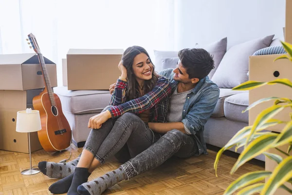 年轻夫妇坐在新家的地板上 拿着纸板箱 — 图库照片