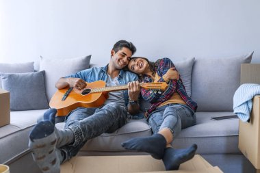Genç adam kız yeni ev için gitar çalmak 