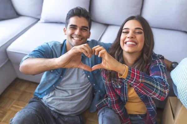 Young couple showing love sign in new home