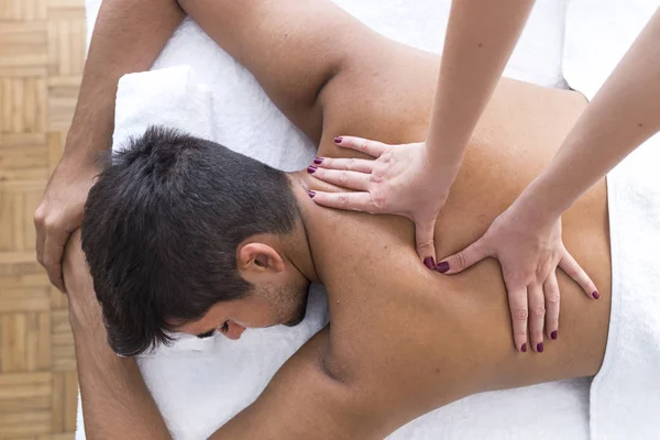 Masseur doing back massage at man in spa salon