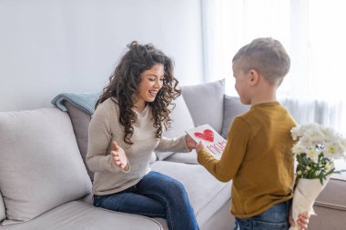 Anne tebrik ediyor ve kartpostal veren küçük çocuk