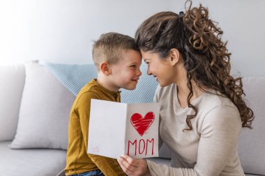 Mutlu oğlu anne tebrik ediyor ve kartpostal kanepede veriyor