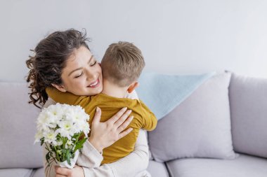 Anne ve buket çiçek kanepede sarılma ile küçük oğlu