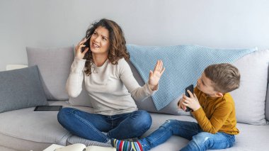 Çoklu görev meşgul anne küçük oğlu oynayan süre telefonda konuşuyor