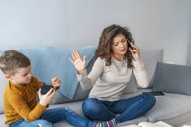 Çoklu görev meşgul anne küçük oğlu oynayan süre telefonda konuşuyor
