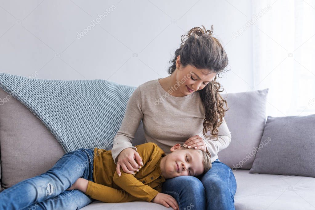 adorable son sleeping on lap of mother on sofa