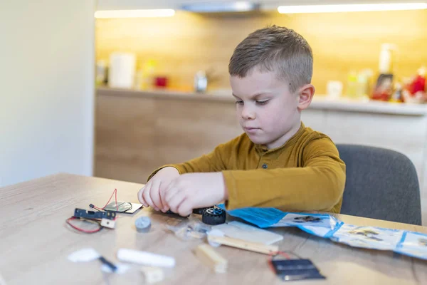 boy concentrating while building robot car at home