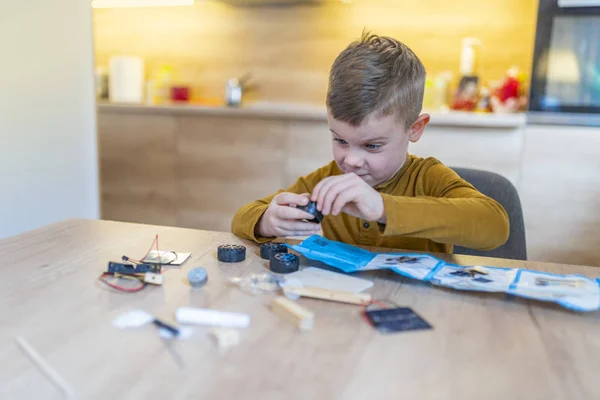 boy concentrating while building robot car at home