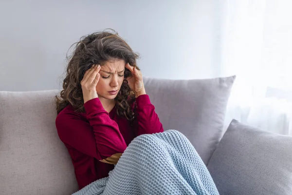 Junge Frau Sitzt Auf Einer Couch Und Hat Starke Kopfschmerzen — Stockfoto