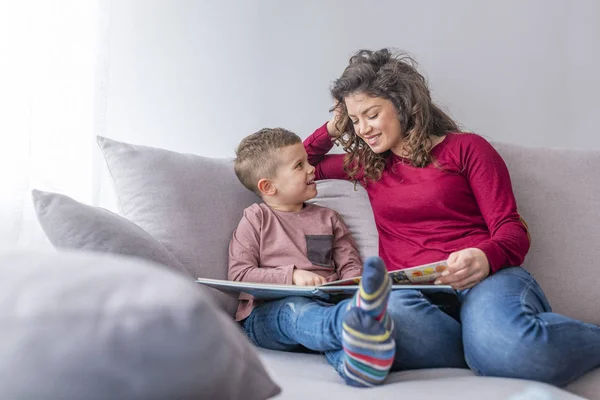 若い女性と小さな息子は ソファの上の本を読んで — ストック写真